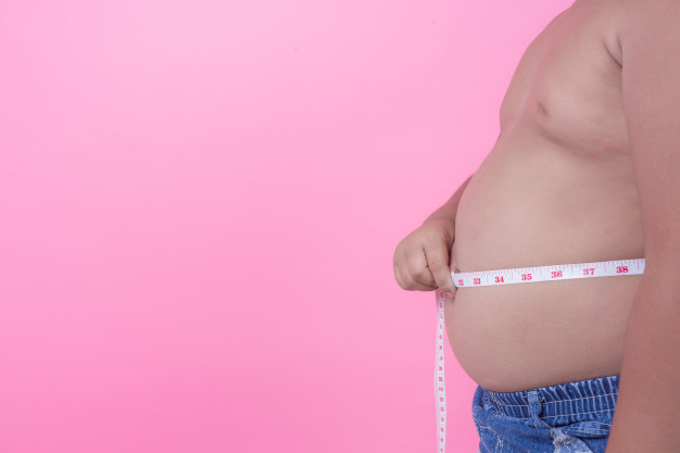 niño con sobrepeso midiendo su barriga.